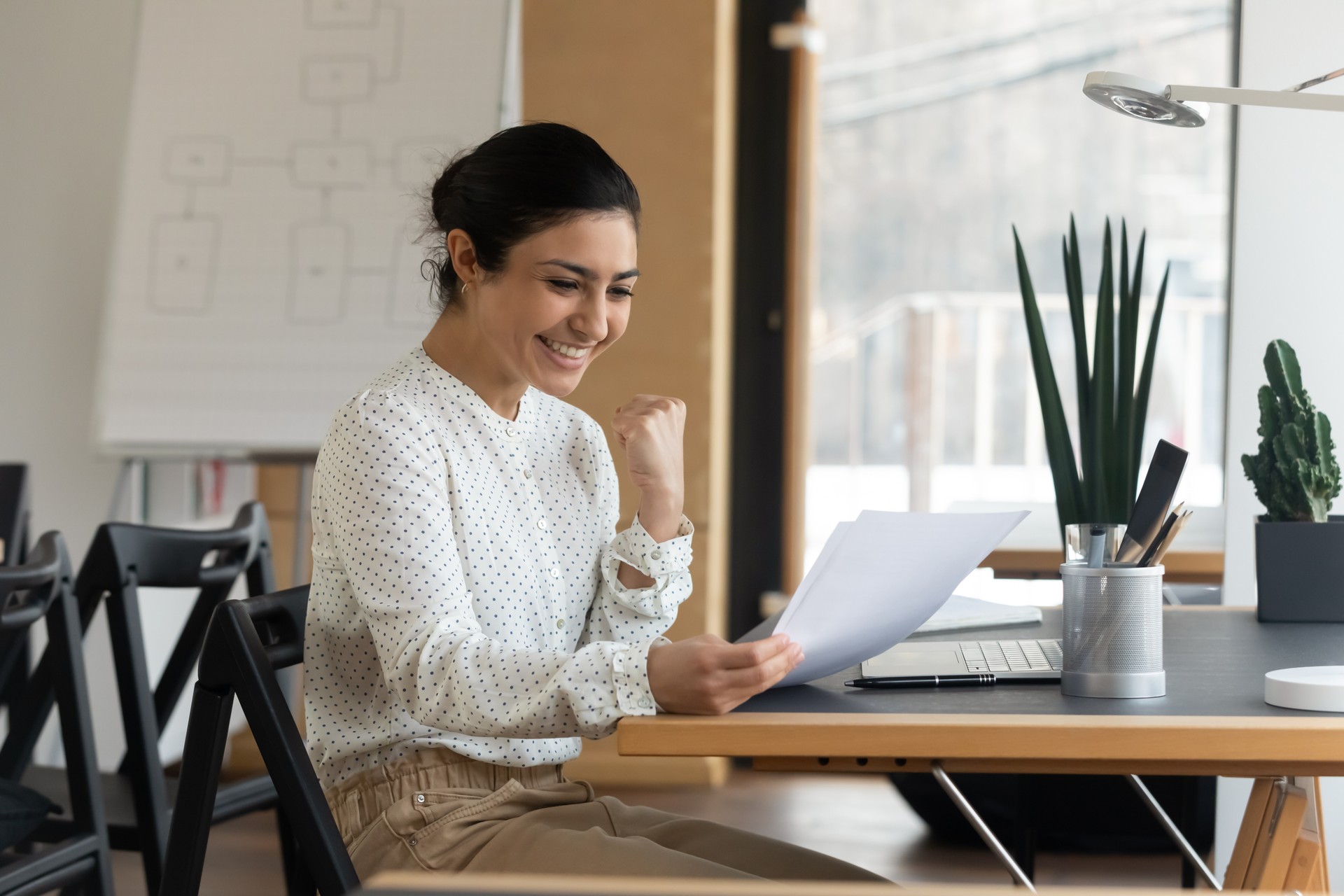 Happy millennial indian woman reading paper letter with good news.