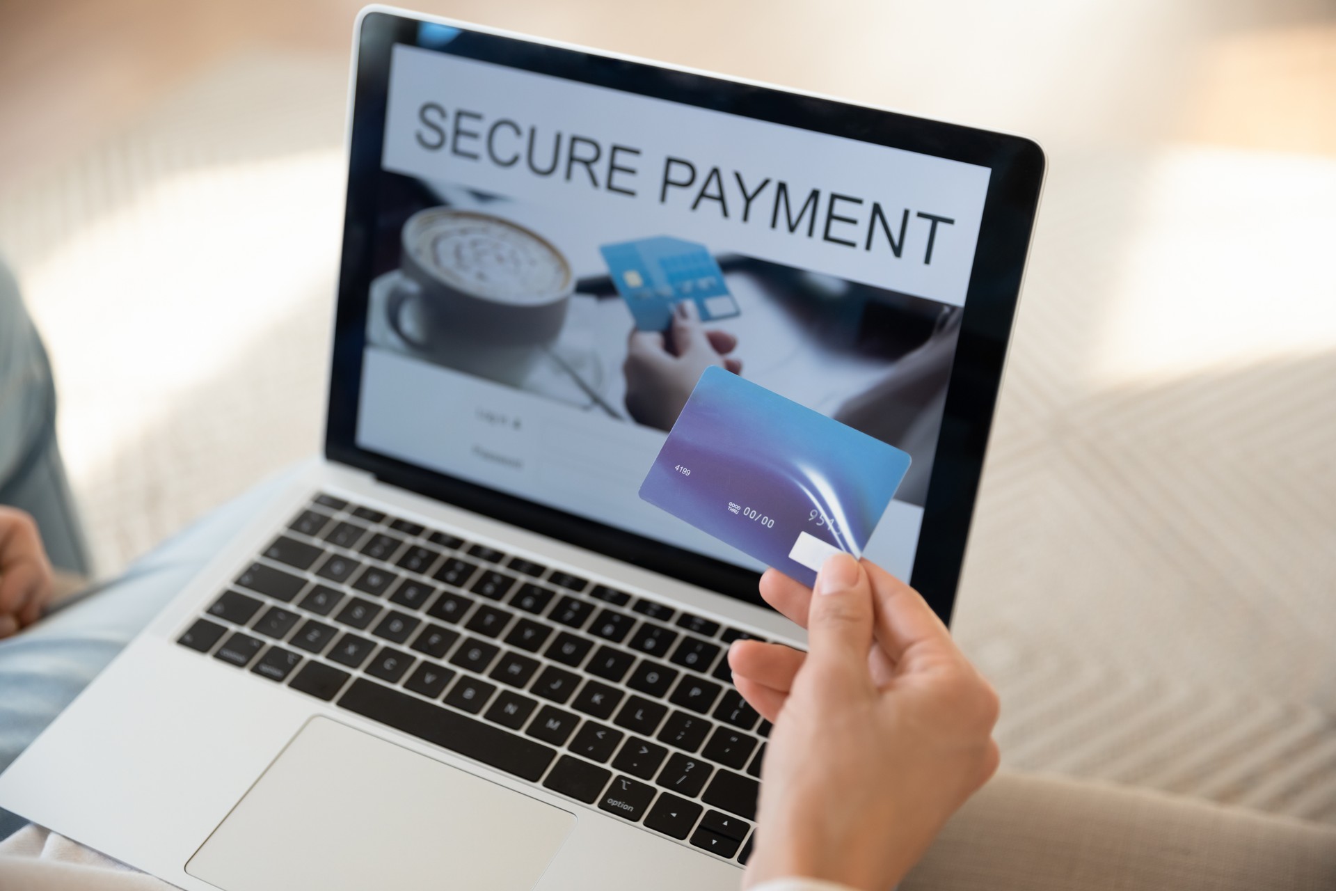 Customer hand with plastic card providing online transactions at laptop